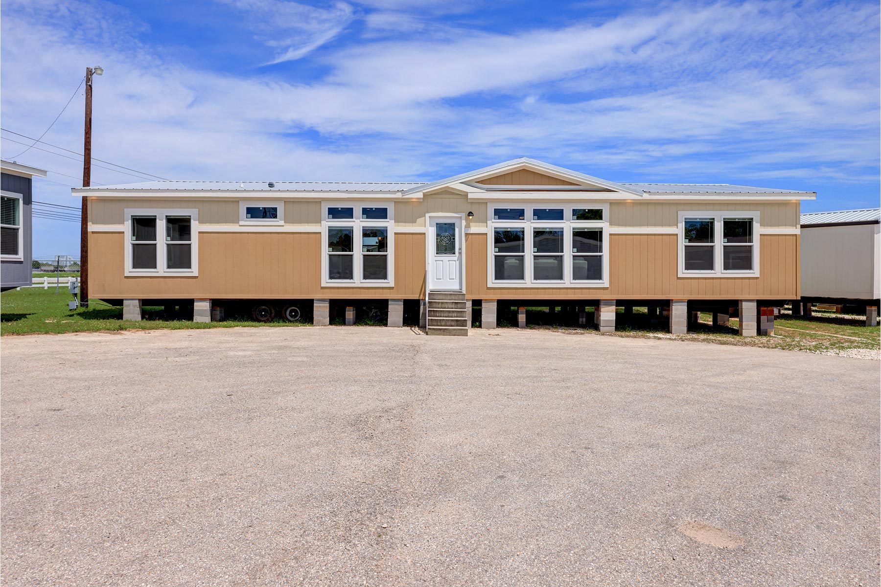 A double-section home standing on piers on the lot at 11500 Central Avenue SE, front elevation with a gabled entry and white-trimmed windows.